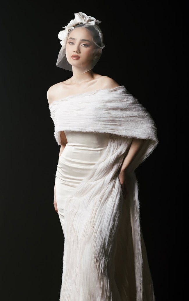 Syifa tampil dengan gaun off-shoulder yang memperlihatkan bahu dan leher, memberi kesan feminin, lembut, dan elegan tanpa terlihat berlebihan. Syifa juga tampak mengenakan veil modern yang unik dengan detail tambahan berbentuk seperti bunga di bagian atasnya. Foto: Intagram/@syifahadju