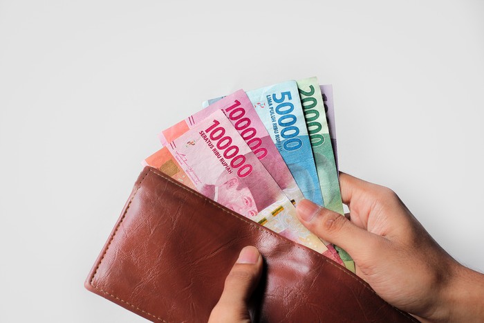 hand showing rupiah money from wallet isolated on white background