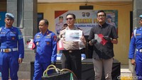 Petugas kepolisian menunjukkan barang bukti berupa ponsel serta dokumen pendukung lain yang diamankan dalam pengungkapan kasus tersebut.