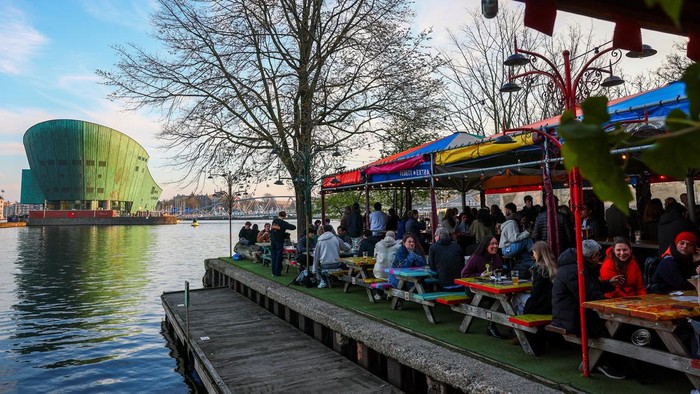 People sit at a terrace next to a canal in Amsterdam, Netherlands, March 19, 2026. REUTERS/Piroschka van de Wouw