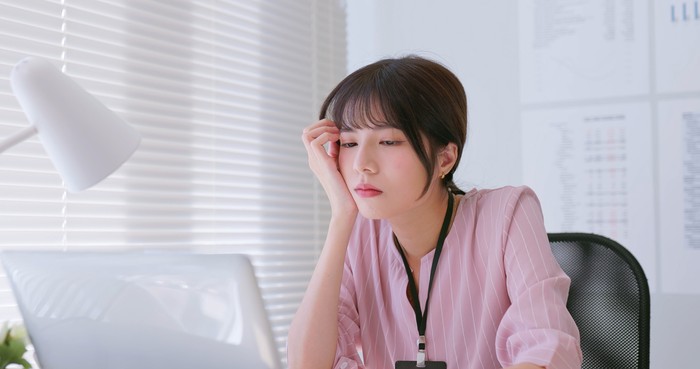 fatigued asian business woman feeling tired exhausted and listless while she is using laptop at office