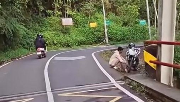 Pria Lumajang, DPW terlihat sedang jongkok menghadap ke arah motor Vixion miliknya sebelum lompat di Jembatan Cangar