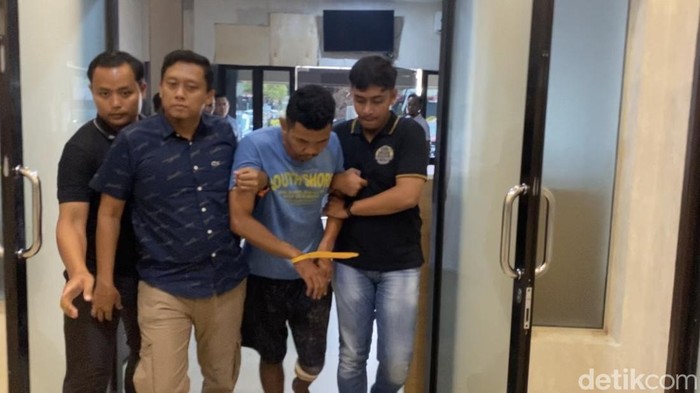 Tersangka saat digiring petugas kepolisian dengan kondisi kaki kanan tertembak. (Mhd Ilham Pradilla/detikSumut)