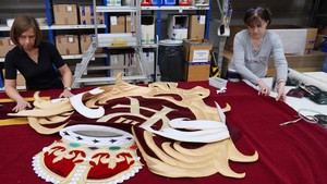 Desain tirai menampilkan sandi kerajaan dengan mahkota dan ornamen klasik. Setelah selesai, bordir tersebut dikirim ke bengkel jahit Gerriets di Volgelsheim di perbatasan Prancis-Jerman. Di sana, para penjahit menerapkan sandi tersebut ke sudut-sudut tirai, yang terbuat dari beludru mohair. Tirai ini terdiri dari dua bagian, masing-masing berukuran lebar 9,75 meter (32 kaki) dan panjang 10,8 meter. Foto: REUTERS/Timm Reichert
