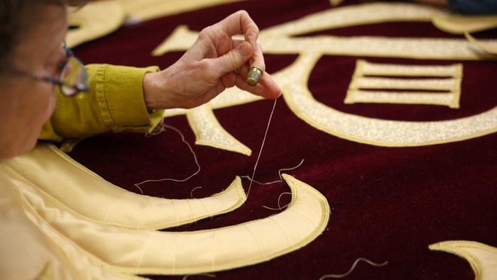 Senior studio embroiderer Helen Stevens hand‑stitches the royal cypher of Britain's King Charles for the new Royal Opera House stage curtains at the Royal School of Needlework, based at Hampton Court Palace, ahead of their unveiling in May 2026, in London, Britain, March 4, 2026. REUTERS/Isabel Infantes