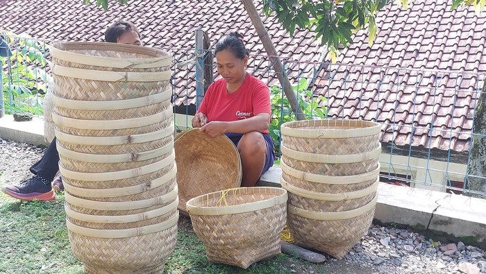 Atika dengan telaten mengayam bakul bambu