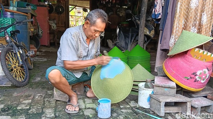 Kardi sedang mengecat topi caping.
