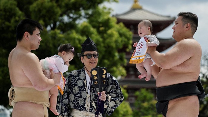 Amateur sumo wrestlers hold babies during 'Nakizumo' or a baby-crying sumo contest, where two wrestlers hold a baby each and a referee makes faces and loud noises to make them cry and determine the winner based on the loudest baby or the first one to cry, at Sensoji temple in Tokyo, Japan, April 25, 2026. The ritual is believed to aid the healthy growth of the children and ward off evil spirits. REUTERS/Issei Kato REFILE - ADDING INFORMATION ABOUT HOW THE WINNER IS DETERMINED