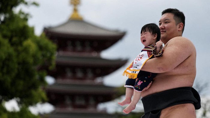 Amateur sumo wrestlers hold babies during 'Nakizumo' or a baby-crying sumo contest, where two wrestlers hold a baby each and a referee makes faces and loud noises to make them cry and determine the winner based on the loudest baby or the first one to cry, at Sensoji temple in Tokyo, Japan, April 25, 2026. The ritual is believed to aid the healthy growth of the children and ward off evil spirits. REUTERS/Issei Kato REFILE - ADDING INFORMATION ABOUT HOW THE WINNER IS DETERMINED