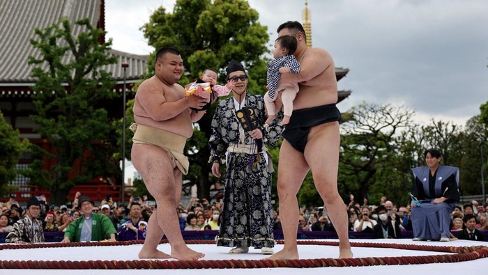 Amateur sumo wrestlers hold babies during 'Nakizumo' or a baby-crying sumo contest, where two wrestlers hold a baby each and a referee makes faces and loud noises to make them cry and determine the winner based on the loudest baby or the first one to cry, at Sensoji temple in Tokyo, Japan, April 25, 2026. The ritual is believed to aid the healthy growth of the children and ward off evil spirits. REUTERS/Issei Kato REFILE - ADDING INFORMATION ABOUT HOW THE WINNER IS DETERMINED