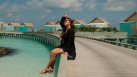 Marsha Aruan asyik duduk di jemnbatan dengan panorama langit cerah dan air laut nan biru. Foto: Instagram @aruanmarsha