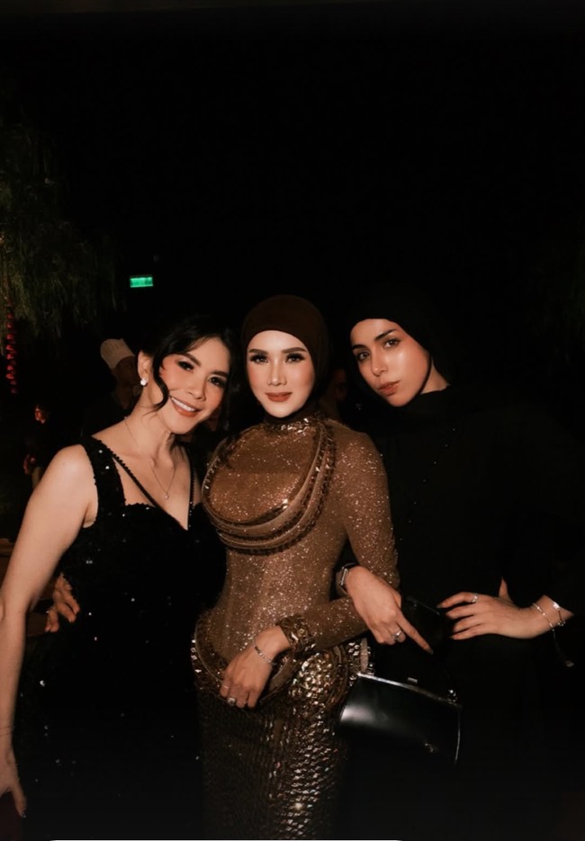 Sementara Mulan tampil dengan gaun bernuansa coklat dan emas dengan struktur yang unik. Terdapat detail kerah tinggi (high neck) dan aksen melingkar di area dada yang dilapisi payet emas. Bagian bawahnya tampak sangat struktural dengan tumpukan elemen dekoratif berbentuk studs emas yang memberikan kesan 3D yang megah. Foto: Instagram/@mulanjameela1
