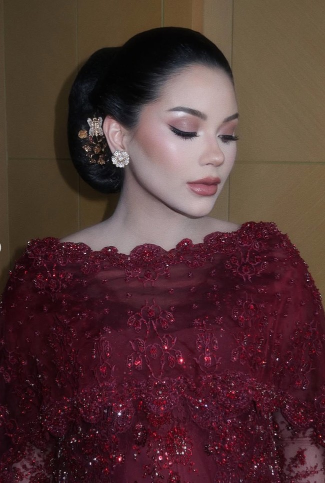 Wajahnya dipulas dengan riasan soft glam dengan sentuhan elegan hasil tangan MUA Rhay David. Kompleksinya tampak flawless dengan foundation full coverage yang halus dan satin finish. Paduan blush peach-rosy yang lembut, contour tipis, serta lipstik nude pink semakin menyempurnakan tampilannya. Foto: Instagram/@rhay_david