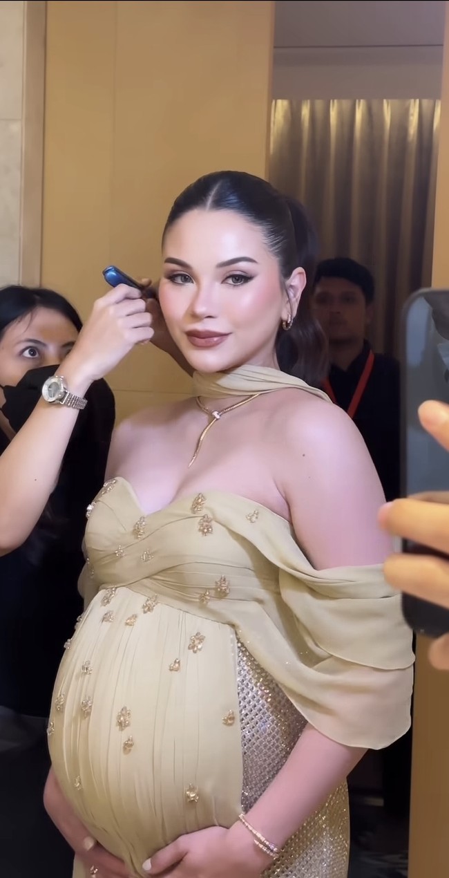 Untuk riasannya, Alyssa kembali mempercayakan pada MUA Rhay David. Kulit tampak flawless dengan complexion satin, dipadukan dengan contour halus untuk mempertegas struktur wajah. Makeup mata menggunakan warna-warna netral dengan sedikit shimmer, eyeliner tipis, dan bulu mata lentik yang memberi efek mata lebih hidup. Bibir dipoles warna nude kecokelatan dengan hasil akhir lembut, selaras dengan tone gaun. Foto: Instagram/@rhay_david