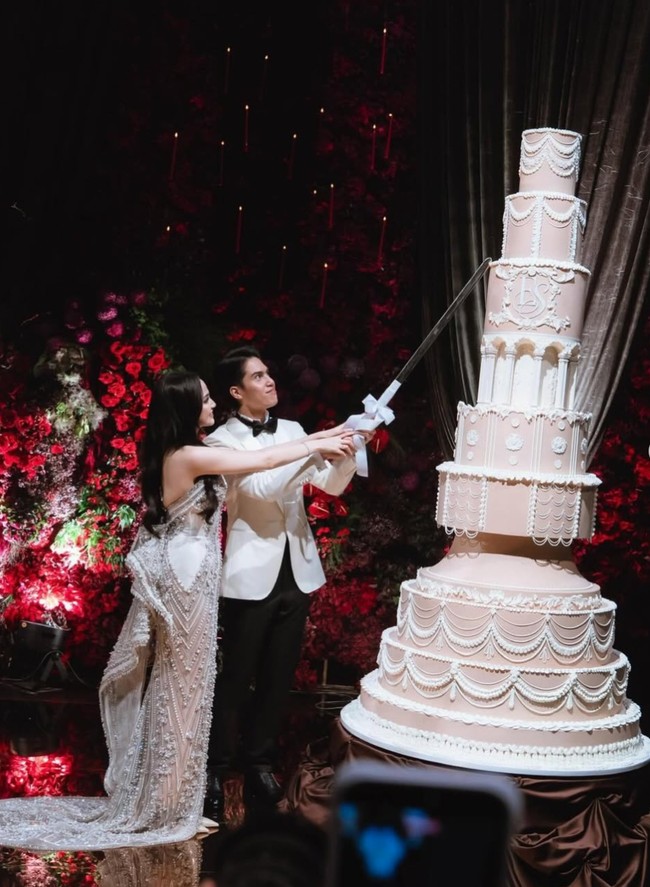 El tampil rapi dengan setelan tuxedo bernuansa putih gading. Jasnya memiliki potongan tailored fit yang pas di badan, dipadukan dengan kemeja putih bersih dan dasi kupu-kupu hitam yang menambah kesan formal. Celana hitam yang dikenakan turut memberi kontras tegas, membuat keseluruhan look terlihat timeless. Foto: Instagram/@thebridedept