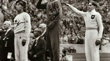 Momen Olimpiade Berlin 1936: Jesse Owens berdiri di podium, sementara atlet Jerman Lutz Long memberi hormat Nazi. Keduanya justru menjalin persahabatan di tengah ketegangan politik. Foto: Boredpanda