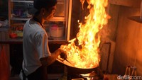Bowo terlihat lihai mengolah nasi di atas wok besar di dapur sederhana dilapaknya. Dengan api membubung tinggi dan gerakan cepat yang mencerminkan teknik dapur profesional.