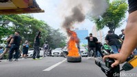 Beberapa massa terlihat membakar ban saat berhenti di depan kantor Kominfo. Asap hitam pekat membumbung sebagai bentuk protes terhadap kebijakan aplikator.