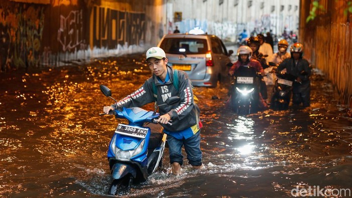 Sejumlah pengendara motor terlihat berusaha memperbaiki kendaraannya yang mogok usai memaksakan diri melintas di Underpass Tambun, Bekasi, Selasa (28/4/2026).