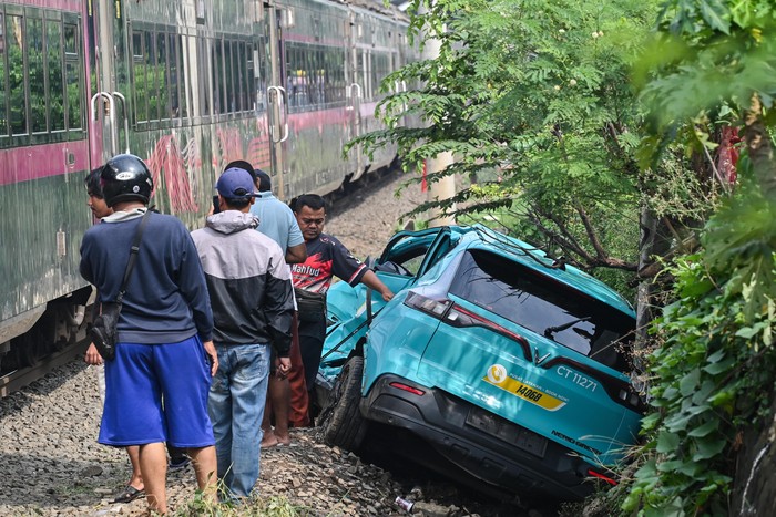 Warga mengamati taksi listrik Green SM  yang rusak pascakecelakaan dengan KRL Commuter Line dan KA Argo Bromo Anggrek di Bekasi Timur, Bekasi, Jawa Barat, Selasa (28/4/2026). Komite Nasional Keselamatan Transportasi (KNKT) mengerahkan tim investigasi