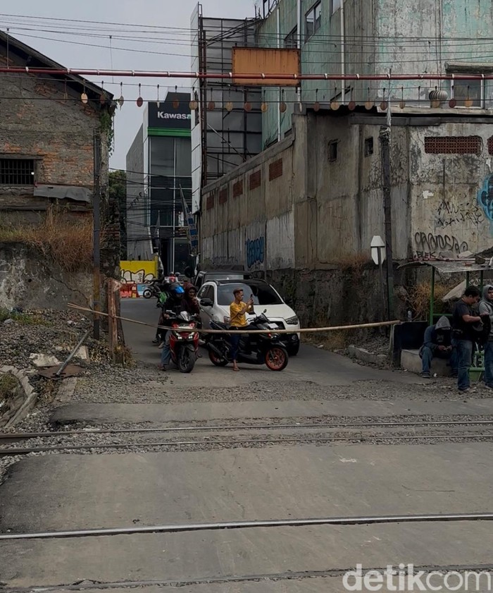 Perlintasan lokasi taksi tertemper KRL di Bekasi Timur hanya ditutup palang bambu. Perlintasan tak resmi tersebut dijaga warga secara bergantian. (Isal M/detikcom)