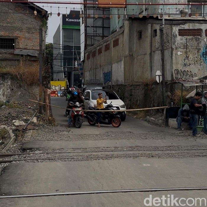 Perlintasan lokasi taksi tertemper KRL di Bekasi Timur hanya ditutup palang bambu. Perlintasan tak resmi tersebut dijaga warga secara bergantian. (Isal M/detikcom)