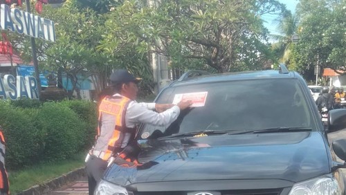 Petugas Dishub Denpasar saat memasang stiker tanda melanggar di ruas Jalan Kamboja dan Jalan Gajah Mada, Rabu (29/4/2026). (dok Dishub Denpasar)