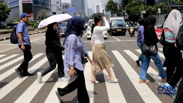 Warga berjalan dengan menutup kepala untuk berlindung dari terik matahari di Sudirman, Jakarta, Rabu (29/4/2026). Warga berjalan dengan menutup kepala untuk berlindung dari terik matahari di Sudirman, Jakarta, Rabu (29/4/2026). (CNBC Indonesia/Muhammad Sabki)