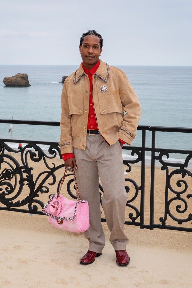 Rapper 37 tahun itu termasuk para bintang yang menghadiri peragaan koleksi Chanel cruise perdana rancangan Matthieu Blazy di pinggir pantai Biarritz, Prancis, pada Selasa (28/4/2026). Berbalut kemeja merah dan jaket camel, serta celana dengan estetika tailoring yang kuat, ia juga tampil percaya diri dengan tas Chanel berwarna pink bubblegum, warna yang kerap diasosiasikan dengan feminitas. (Foto: B Lacroix/Getty Images for Chanel)