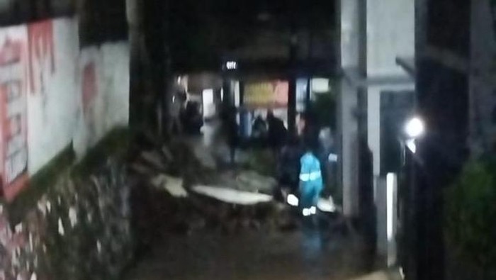 Hujan deras mengguyur kawasan Kota Depok, Jawa Barat (Jabar). Intensitas hujan yang deras membuat tembok roboh karena tanah longsor tergerus air. (dok Damkar Depok)
