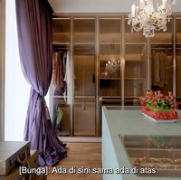 Area lemari kaca yang berdesain minimalis untuk pakaian mendapat sentuhan mewah lewat lampu gantung klasik. Di bagian tengah, terdapat semacam island yang didedikasikan untuk menyimpan koleksi perhiasannya. (Foto: TikTok/@kiaisauraa)