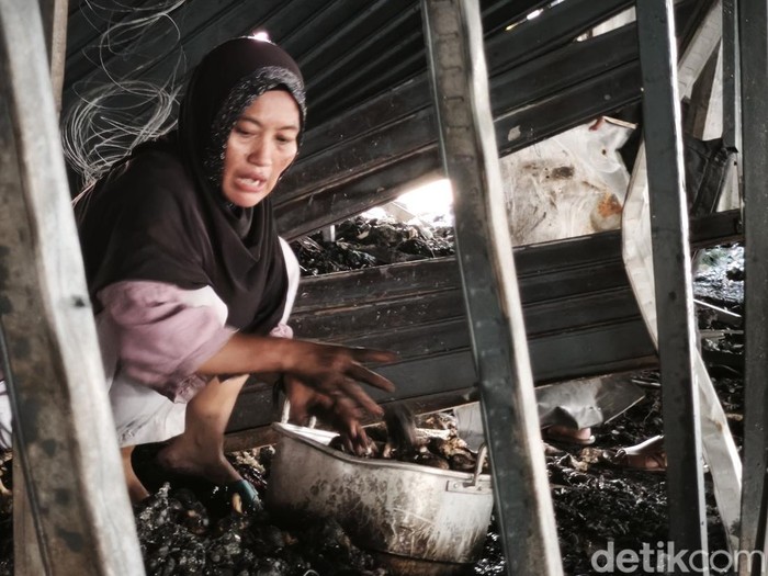 Seorang pedagang bahan pangan di Pasar Kanjengan, Ningsih, saat mengais sisa bawang putih yang terbakar, Kamis (30/4/2026).