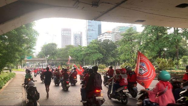 Sejumlah massa buruh melakukan konvoi mengikuti perayaan Hari Buruh Internasional atau May Day 2026 ke Monas, Jakarta Pusat. Mereka mengenakan baju senada dan membawa bendera asosiasi.