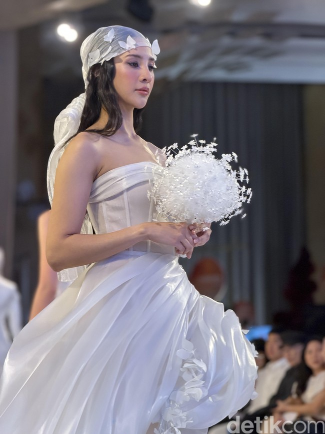 Ia melengkapi penampilannya dengan aksesori kepala transparan berhias bunga serta buket putih yang memperkuat nuansa bridal. (Foto: Daniel Ngantung/detikcom)