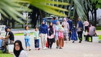 Pengunjung berjalan santai menyusuri taman di sore hari. Lonjakan hari libur dalam satu bulan memberi ruang bagi warga untuk memperlambat ritme aktivitas.