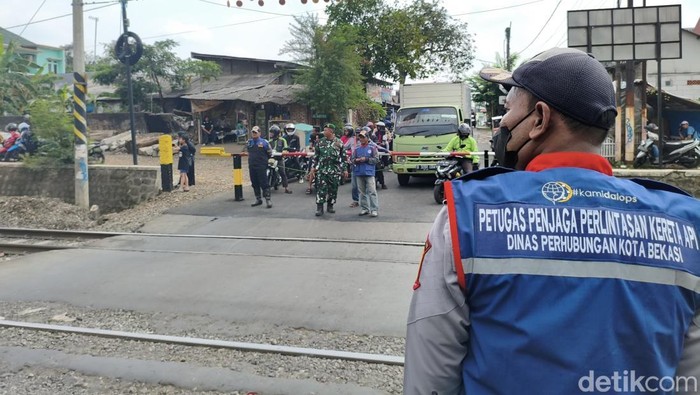 Perlintasan sebidang liar di Jalan Ampera, Kota Bekasi, yang jadi lokasi taksi hijau tertemper kereta sebelum insiden tabrakan KA kini dijaga petugas. (Fadil/detikcom)