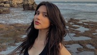 Davina Karamoy membagikan foto liburan di salah satu pantai di Indonesia. Pemandangannya begitu indah dengan tebing karang tinggi di belakang dan bebatuan di sekitarnya. (Foto: dok Instagram davinaakaramoy)