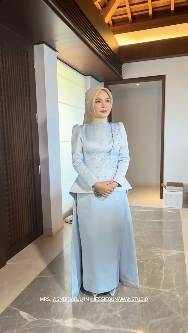 Sementara ibunda Syifa, Shendy, tampil dengan atasan berbentuk peplum yang menonjolkan pinggang dan memberi struktur pada tubuh. Gaun tersebut dilengkapi payet atau kristal membentuk motif abstrak yang menjalar dari bahu ke bagian dada. Bagian bahunya sedikit puff (bervolume) sehingga memberi siluet tegas dan elegan. Shendy kemudian melengkapi penampilannya dengan hijab polos berwarna nude. Foto: Instagram/@jessiegunawanstudio