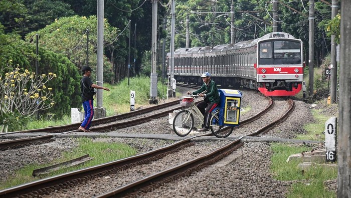 Sejumlah pengendara motor menunggu untuk menyeberangi jalur perlintasan kereta sebidang di kawasan Tanah Kusir, Kebayoran Lama, Jakarta, Minggu (3/5/2026). PT Kereta Api Indonesia (Persero) (KAI) mencatat sebanyak 130 perlintasan kereta sebidang belu