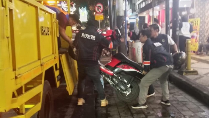 Petugas Dinas Perhubungan mengangkut motor yang parkir di tepi koridor Kayutangan