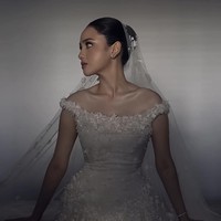 Gaun Syifa dibuat secara custom menggunakan kombinasi bahan silk organza dan gazar, yang dikenal ringan namun tetap mampu memberi struktur pada siluet. Detail paling mencuri perhatian ada pada aplikasi bunga tiga dimensi yang tersebar dari bodice hingga rok.  Foto: Instagram/@hiantjen