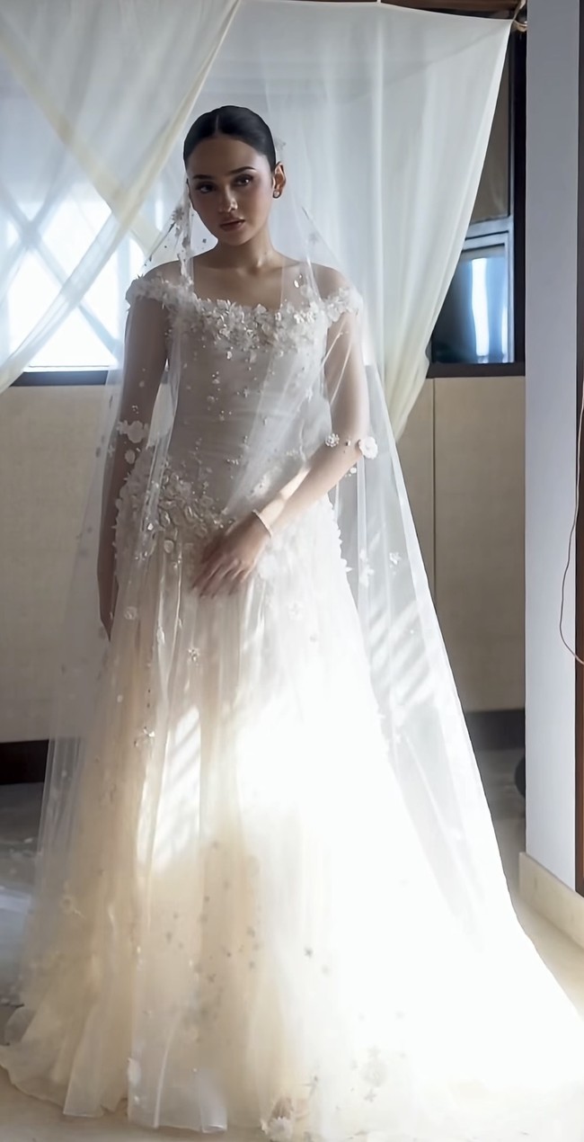 Roknya berbentuk A-line penuh dengan layer ringan yang membuatnya tampak mengembang namun tidak berat. Material organza yang transparan berlapis memberi efek flowy dan dreamy saat bergerak. Gaun ini disempurnakan dengan veil panjang berhias motif bunga senada. Foto: Instagram/@hiantjen