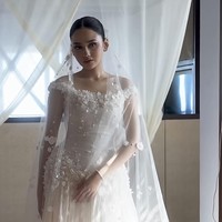 Roknya berbentuk A-line penuh dengan layer ringan yang membuatnya tampak mengembang namun tidak berat. Material organza yang transparan berlapis memberi efek flowy dan dreamy saat bergerak. Gaun ini disempurnakan dengan veil panjang berhias motif bunga senada. Foto: Instagram/@hiantjen
