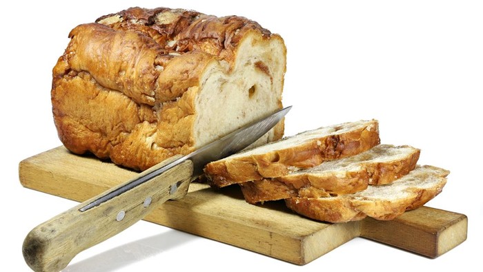 Frisian Suikerbrood (sugar bread) with knife and wooden plate isolated on white background