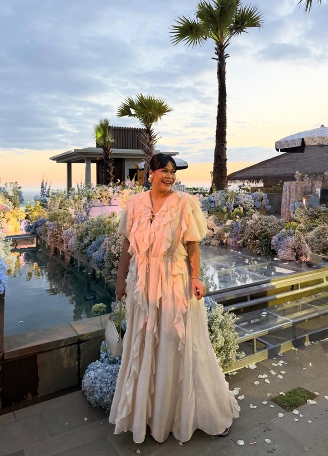 Okky Lukman memilih tampil memukau dengan dress panjang berwarna krem. Dress tersebut dipenuhi detail ruffle yang menjalar dari bagian bahu sampai bawah kakinya. Foto: Instagram