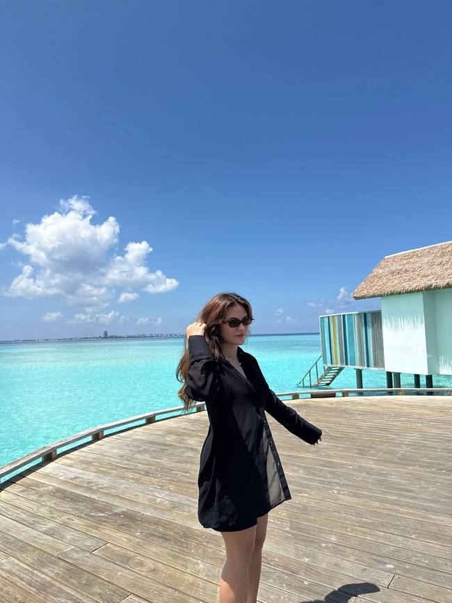 Berjemur di bawah sinar matahari dengan latar langit dan laut biru, Marsha mengenakan busana hitam yang kontras. Shirt dress dipadu celana pendek menampilkan gaya casual yang tetap stylish. Foto: Instagram/@marshaaruan