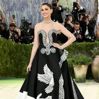 Anne Hathaway tampil elegan dalam gaun custom Michael Kors hasil kolaborasi dengan seniman Peter McGough, di mana gaun hitam strapless itu menjadi kanvas lukisan tangan penuh simbol perdamaian, flora, dan narasi puitis yang terinspirasi dari Ode on a Grecian Urn, memadukan siluet klasik dengan storytelling artistik. Foto: Getty Images