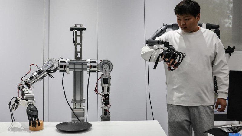 An ensemble of humanoid robots produced by Linkerbot is set up with musical instruments as a woman holding a wipe walks nearby, at the company’s office in Beijing, China, April 27, 2026. REUTERS/Maxim Shemetov
