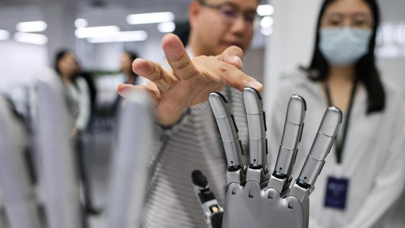 An ensemble of humanoid robots produced by Linkerbot is set up with musical instruments as a woman holding a wipe walks nearby, at the company’s office in Beijing, China, April 27, 2026. REUTERS/Maxim Shemetov