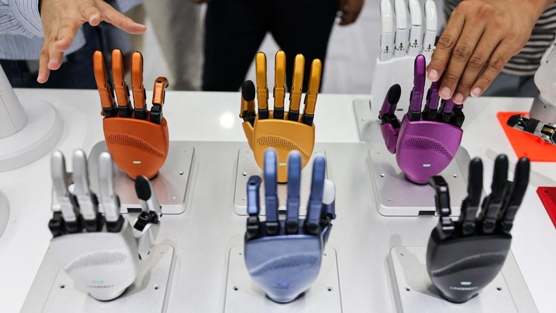 An ensemble of humanoid robots produced by Linkerbot is set up with musical instruments as a woman holding a wipe walks nearby, at the company’s office in Beijing, China, April 27, 2026. REUTERS/Maxim Shemetov